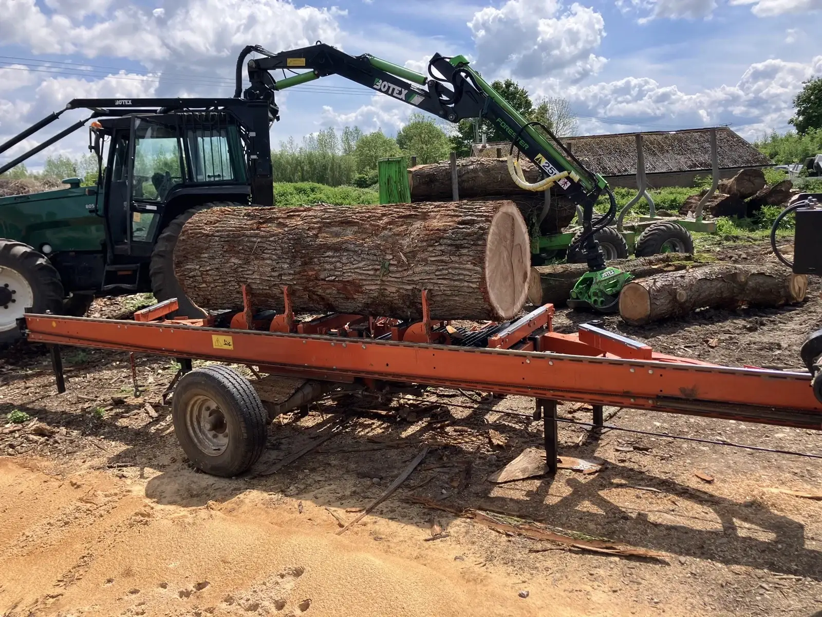 An English cherry log being loaded onto the sawmill bed by tractor grab, Long Wittenham