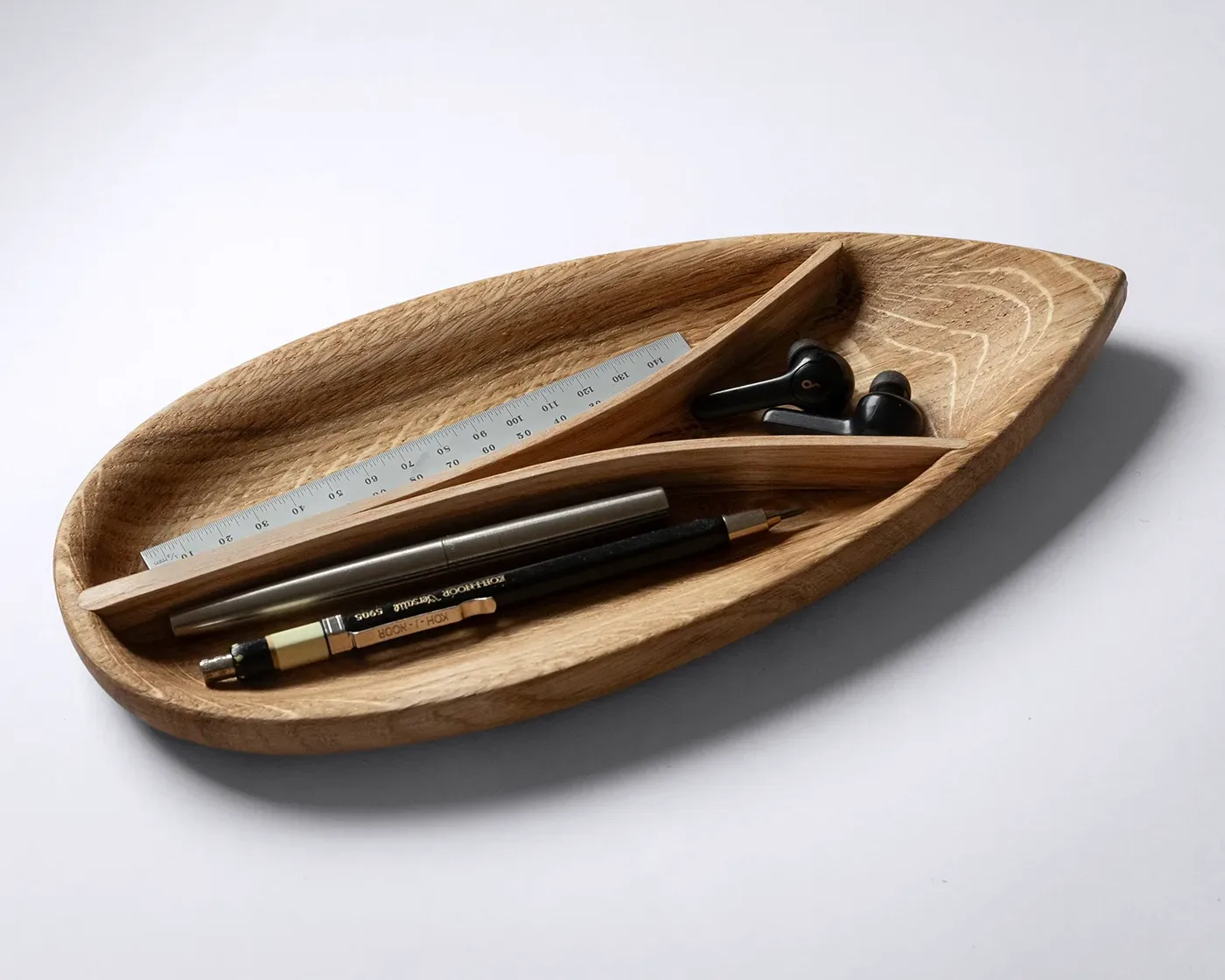 Steam-bent wooden desk tray in oak, overhead view showing the teardrop form and three compartments
