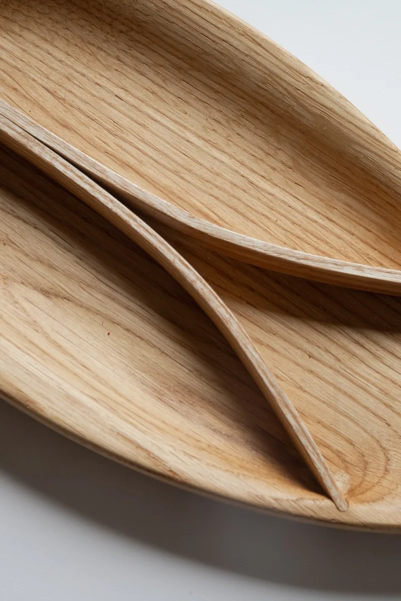 Bent wood tray in oak with ash dividers on a clean white surface, showing the leaf-shaped form