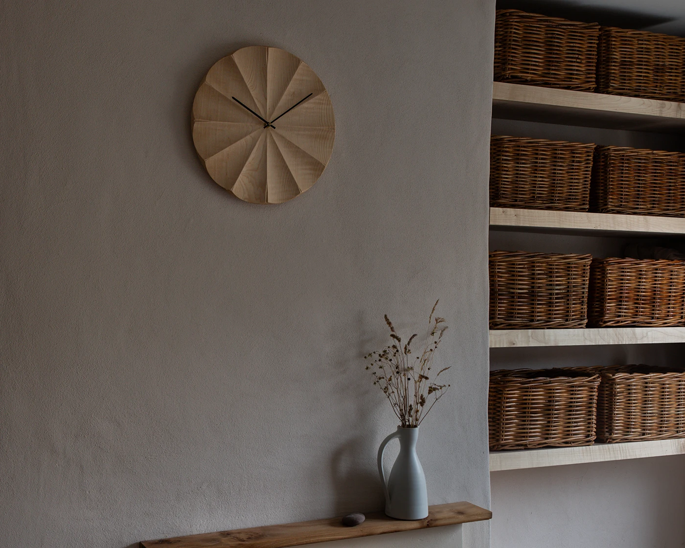 British sycamore wall clock with radial fluted face hanging above a fireplace in a contemporary interior