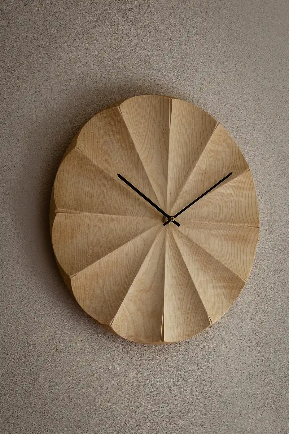 Fluted sycamore wall clock showing the radiating carved face and black clock hands