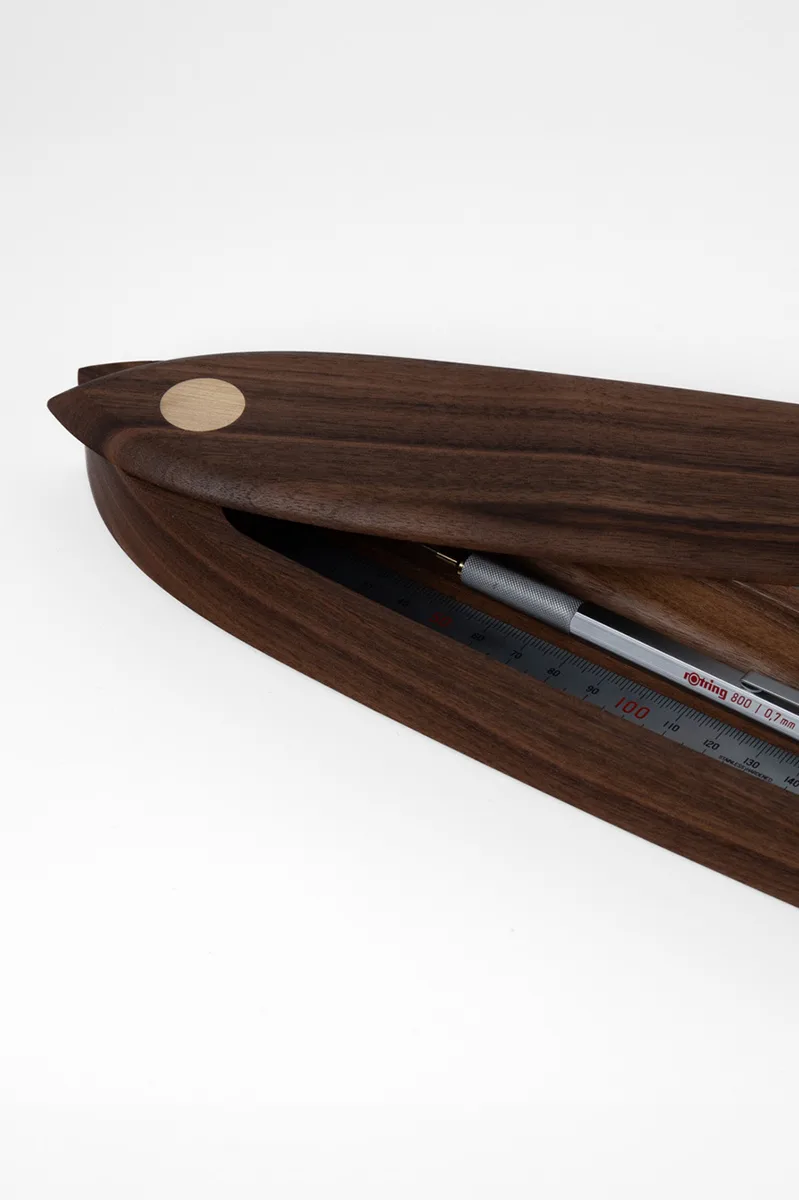 Walnut pen box with lid slightly open, showing the grain and brass pivot inlay