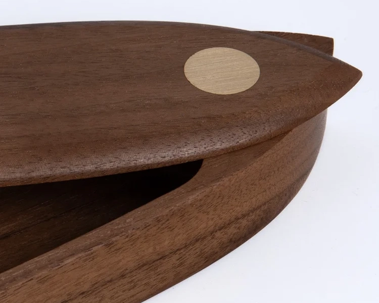 Close-up of the pen box lid showing the round brass pivot inlay and walnut grain detail