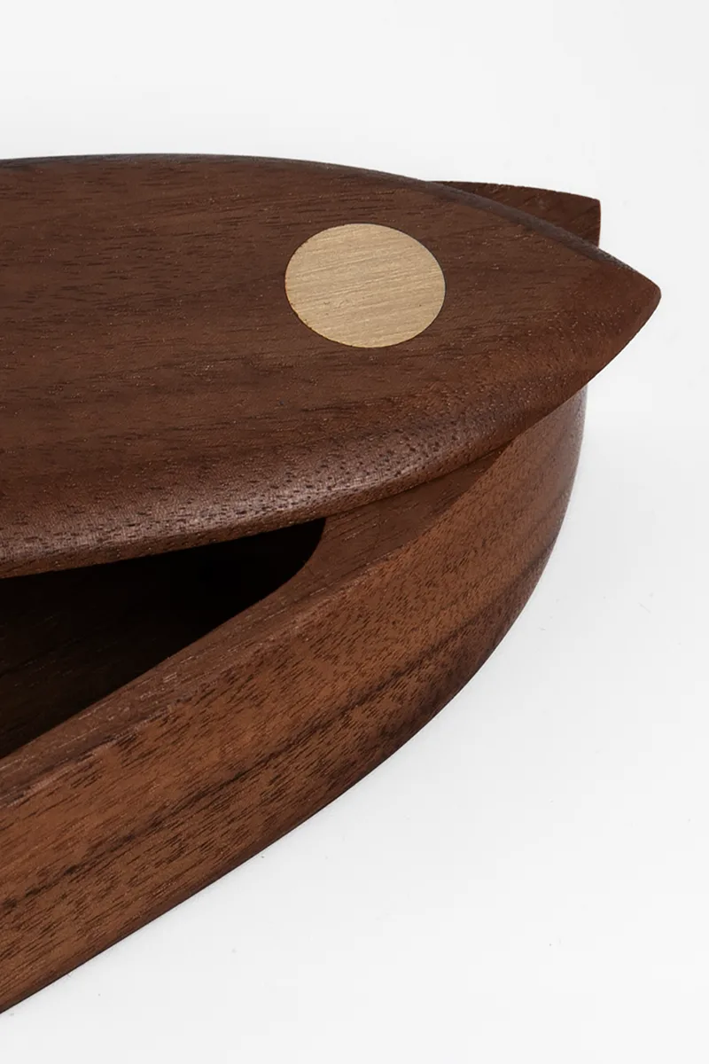 Close-up of the pen box lid showing the round brass pivot inlay and walnut grain detail